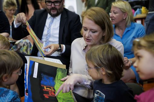 Auf dem Bild schauen sich Bundesfamilienministerin Lisa Paus und Sachsens Kultusminister Christian Piwarz - umringt von Kindern - Bilder der Kleinen an.